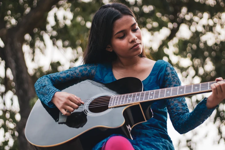 a girl with a blue dress playing the guitar