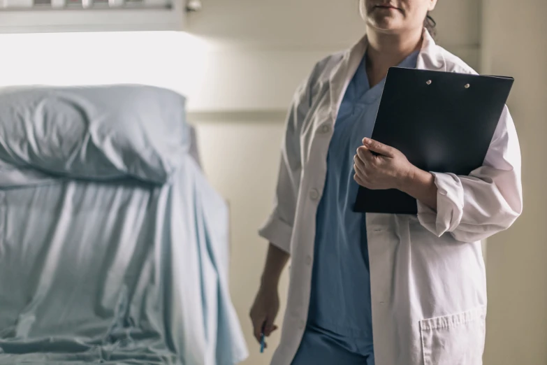 a man in white coat holding a clipboard in room