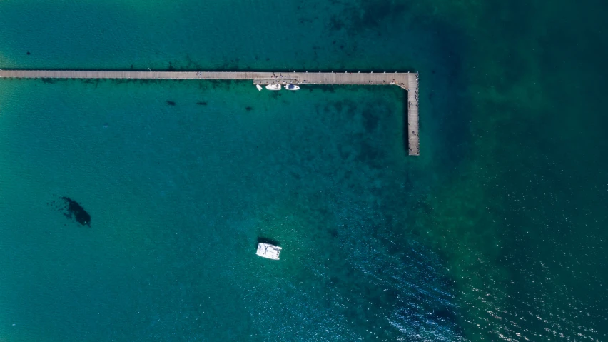 an aerial view of a body of water and some wooden dock with a sail boat