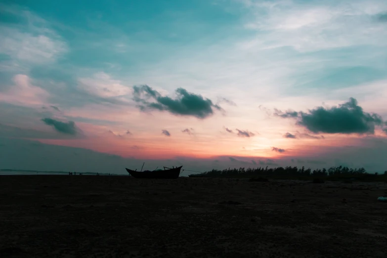 a beach with a boat on it at sunset