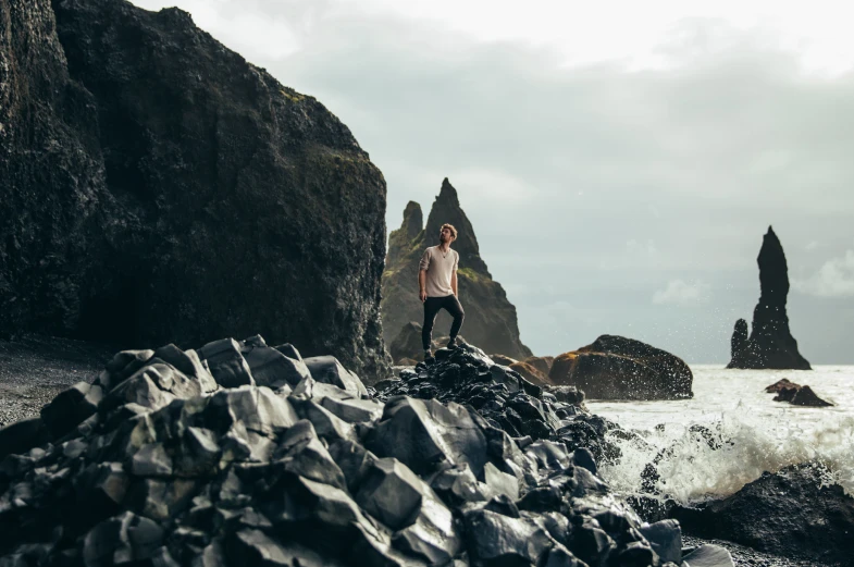 a man stands on top of rocks on the beach