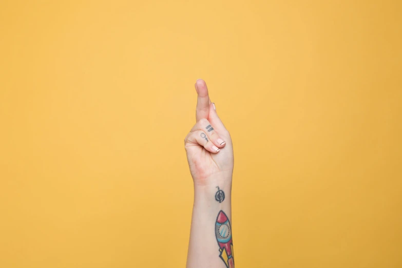 a woman points to a space themed finger tattoo on her thumb