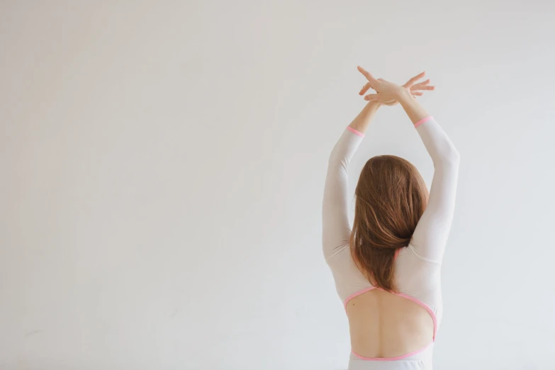 a woman wearing a light pink leotard stretching her arms in the air