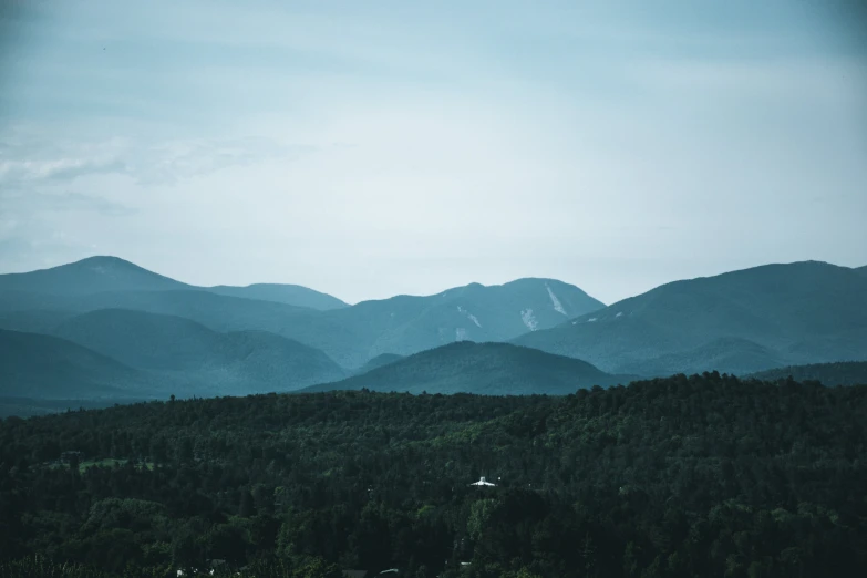 a mountain view with green hills and a forest