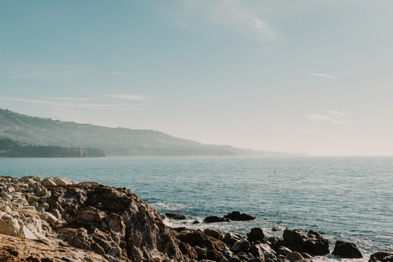 a person sitting on a rocky outcropping near the ocean