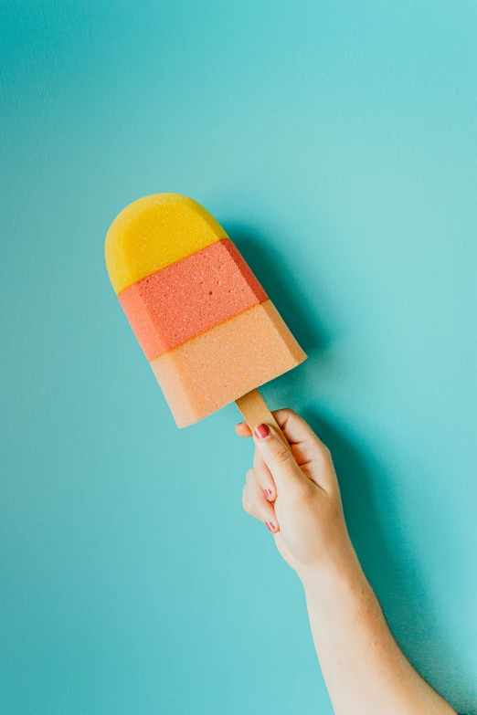 a person holding a popsicle painted orange and yellow