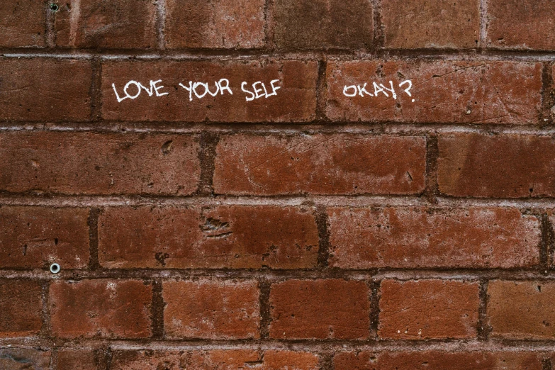the words love yourself and only written on a brick wall