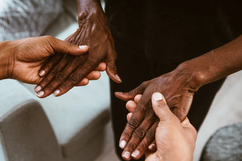 four people are shown holding their hands together