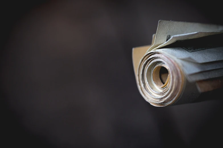 an empty rolled up piece of newspaper sits on a dark surface