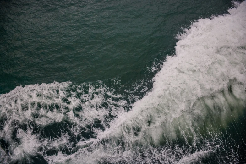 a large wave coming up over a ship with it's bottom