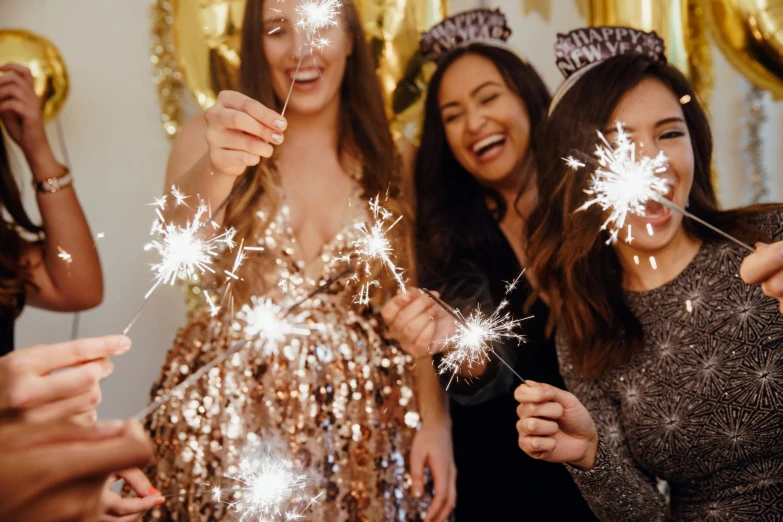 two girls wearing party hats standing around holding sparkle wands