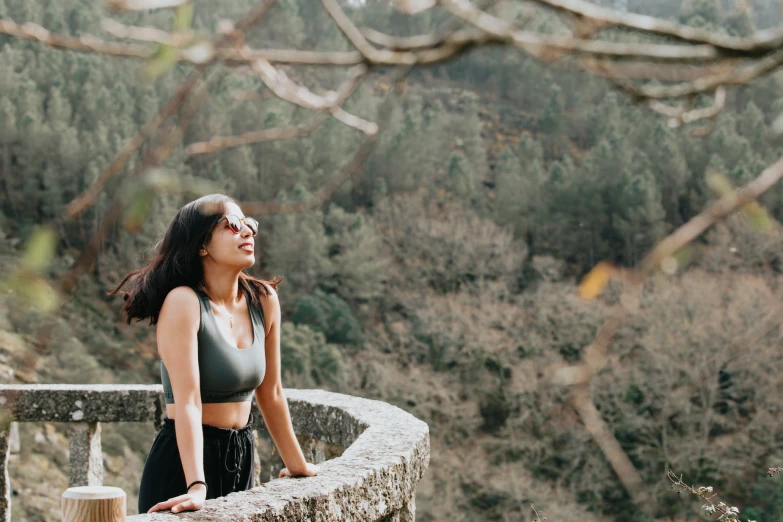 the woman in the grey  top is leaning against a wall