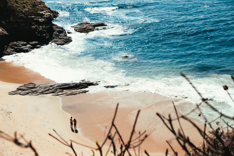 two people standing at the beach on the sand