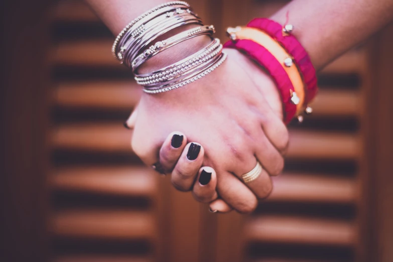 a pair of people holding hands with celets on their arm
