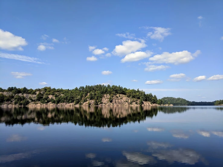 calm blue water with clouds reflecting on the shore