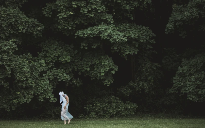 a person standing in a field under some trees