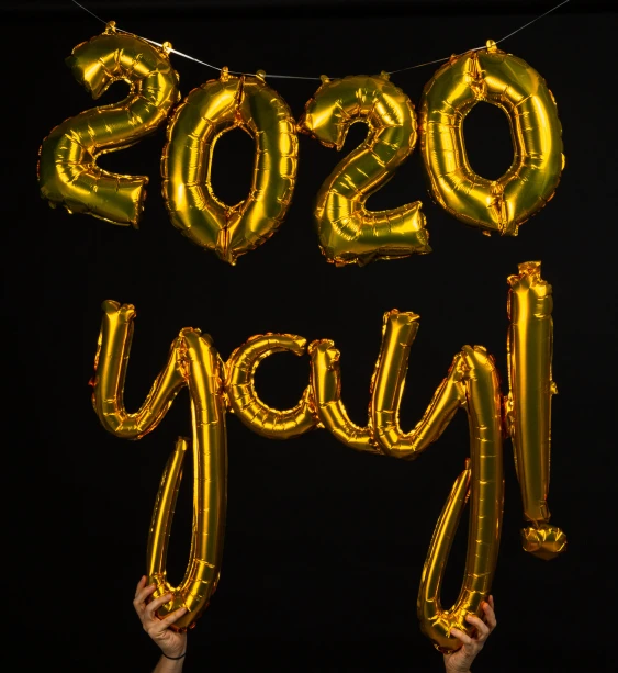 a hand holding a large gold foil number balloon