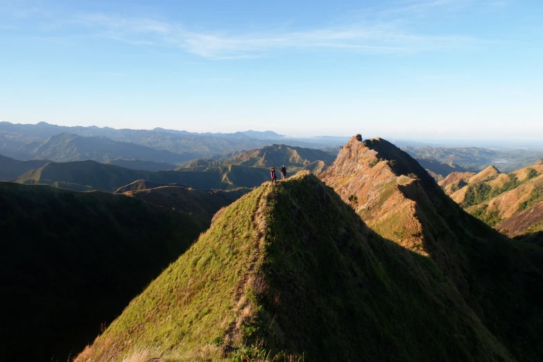 a couple of people sitting on top of a big green mountain