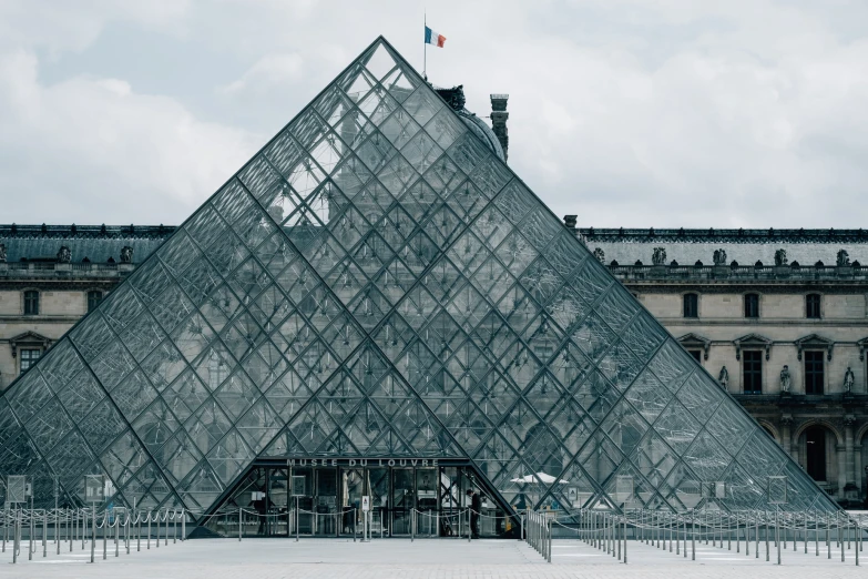 the glass pyramid of the museum is in front of a building