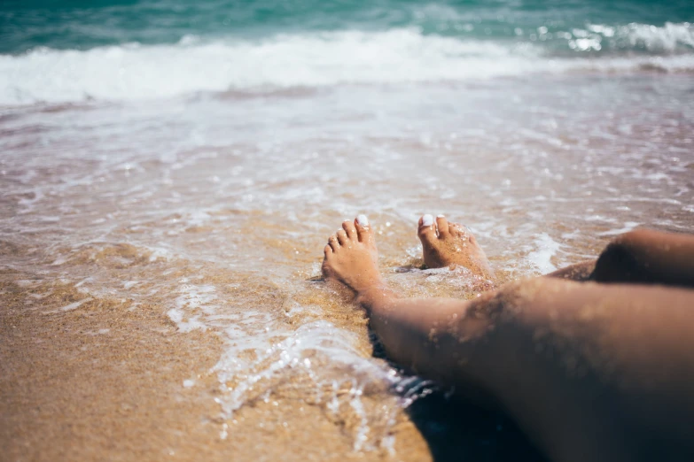 a person's feet sticking out of the waves