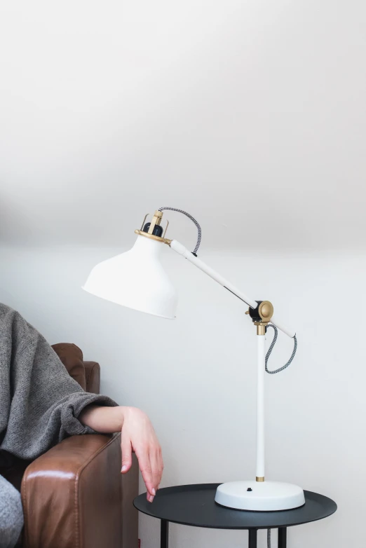 a small table with a lamp on top and the person is sitting next to it