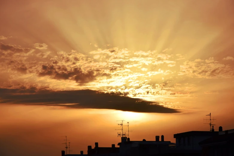 the sun shining down on some buildings as seen from a rooftop