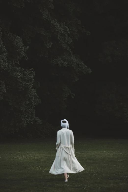 a person in a white dress walking through the grass