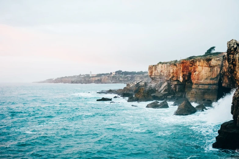 large rocky cliff on shore with ocean and trees