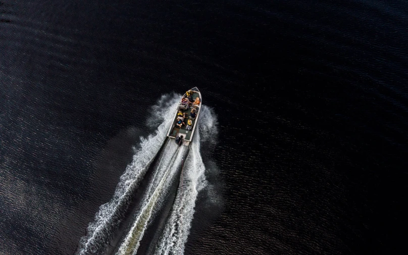 a boat speeds through the ocean near the shore