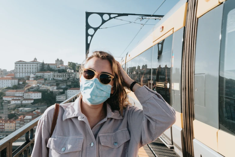 a woman wearing a surgical face mask near a train