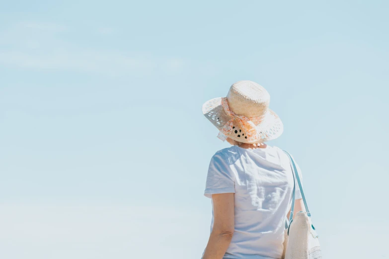 a woman standing with her back turned wearing a hat