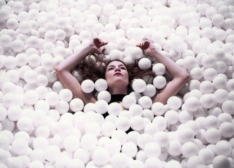 a woman in the water surrounded by white balls