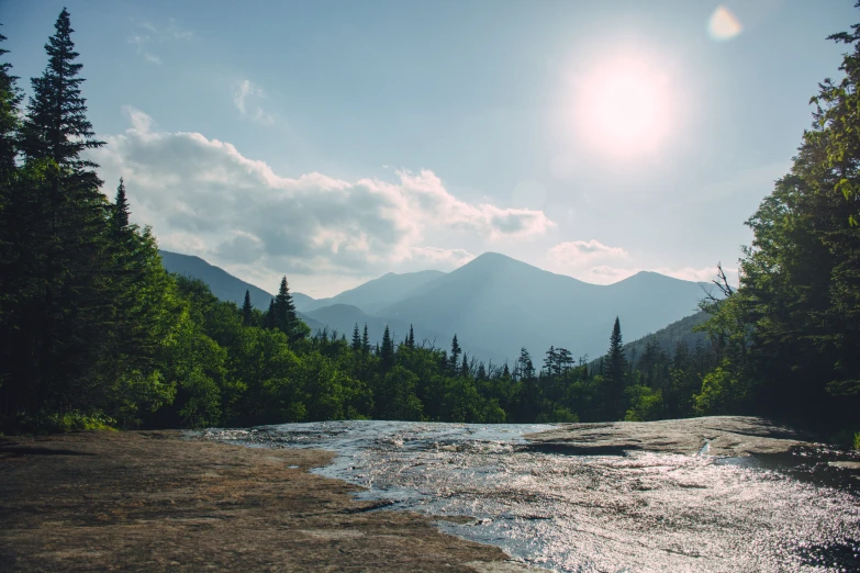 a small stream of water with mountains in the background