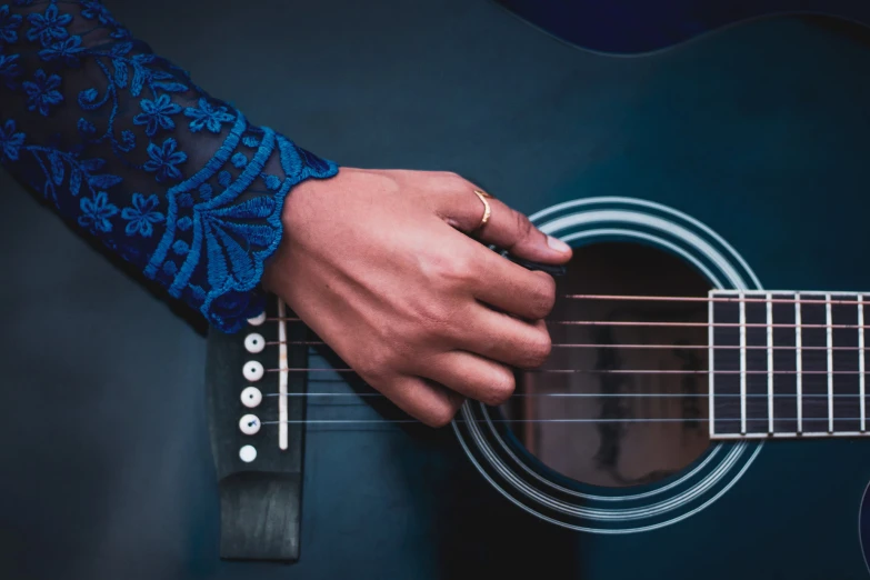 two hands and a guitar on a blue backdrop