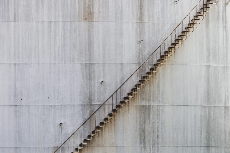 a very long staircase next to a big gray wall