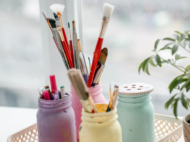 the jars are holding pens and brushes on the counter