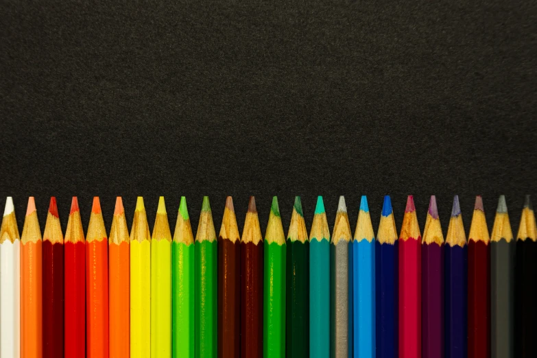 a row of colored pencils against a black background