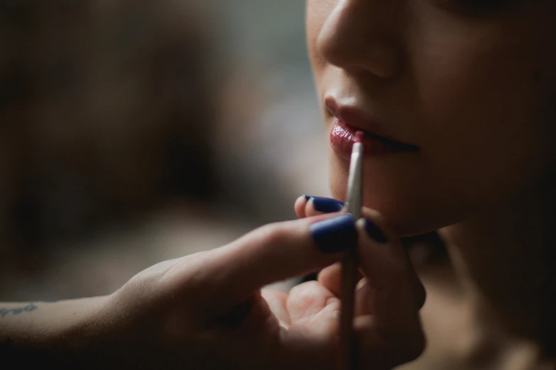 the woman is putting on lipstick for her face