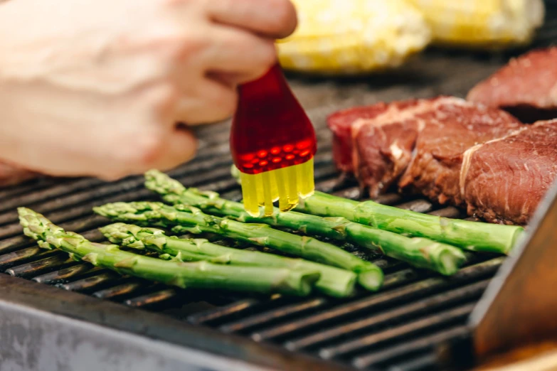 a steak on top of an outside grill with asparagus being pulled through