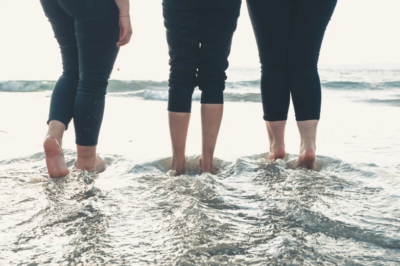 two women's feet are standing in the water