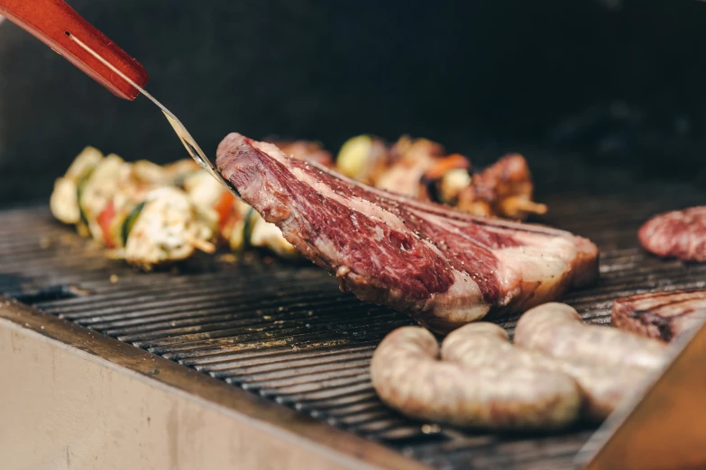 a person cooking meat on top of a grill