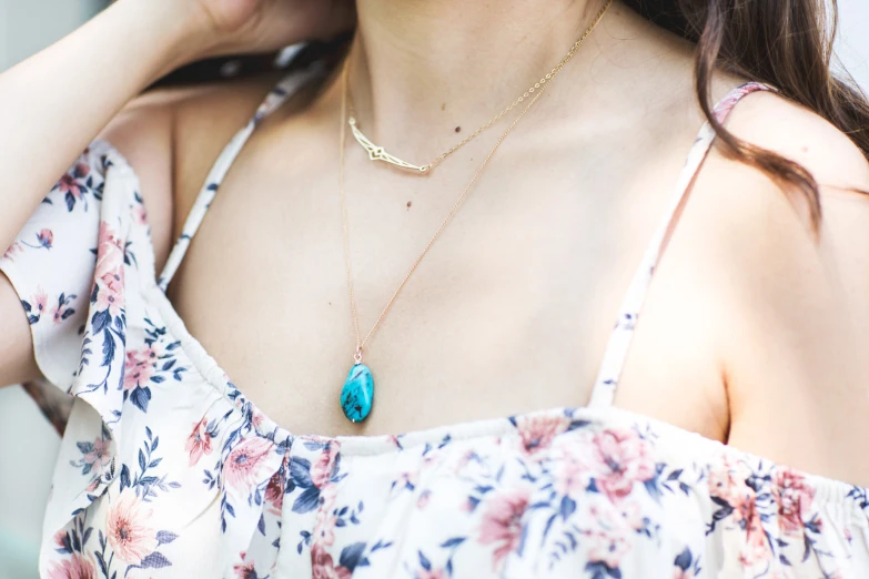 a woman wearing a necklace that has a turquoise stone