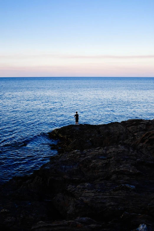 a lone figure on the shore of a large body of water