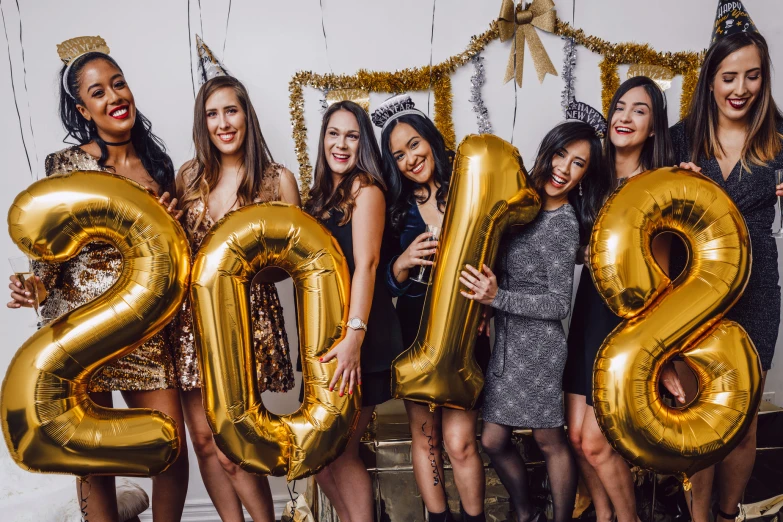 several women posing with large gold balloons and the numbers 2012