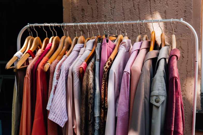 multiple shirts hanging on a clothing rack by the wall