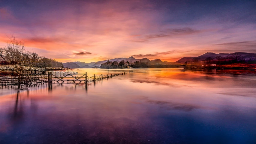 sunset over the water with long dock on water