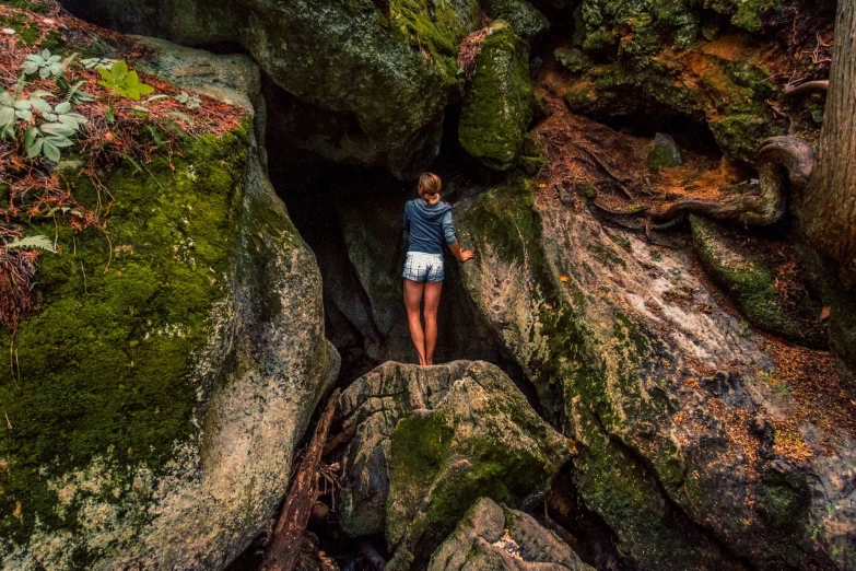 a person climbing up a rocky area with lots of moss on it