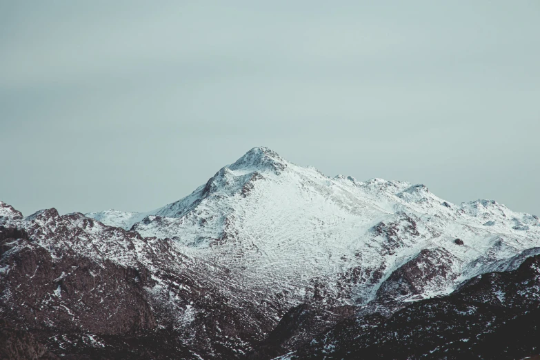 a snow - covered mountain side with clouds overhead