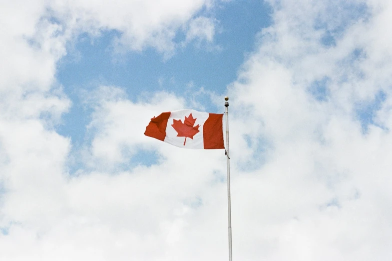 the canadian flag blowing in the wind on a cloudy day