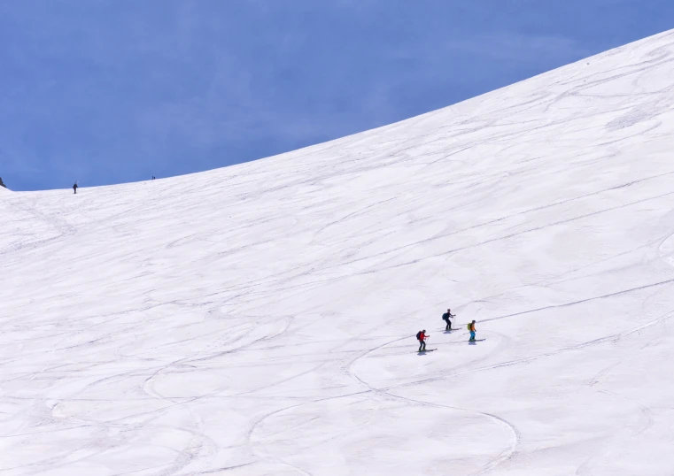 three people on skis trekking up a steep white slope